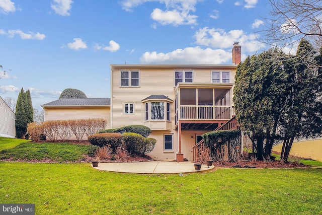 back of property with a sunroom, a patio area, and a yard