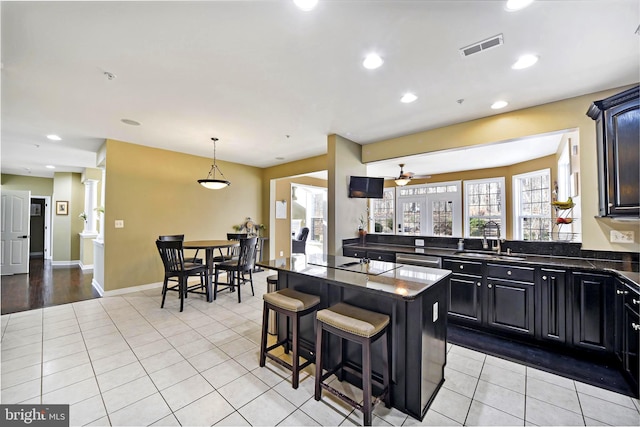 kitchen with a kitchen bar, black electric stovetop, ceiling fan, sink, and light tile patterned floors