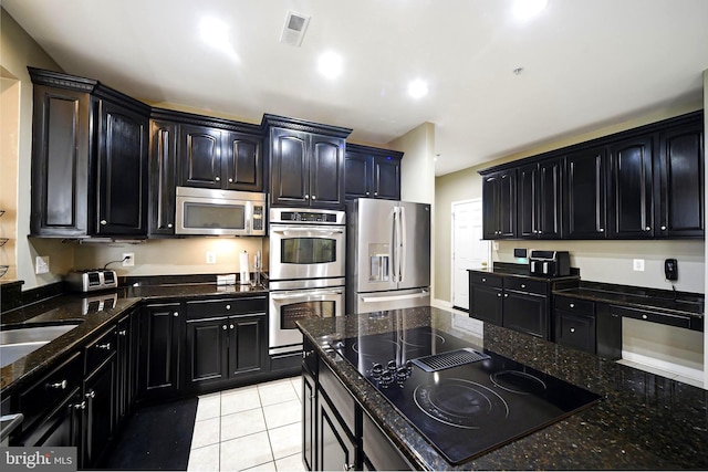 kitchen featuring dark stone countertops, sink, light tile patterned floors, and stainless steel appliances