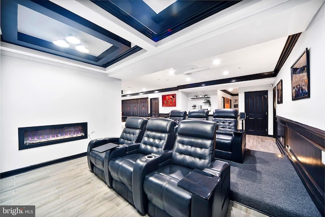 home theater room with a raised ceiling and ornamental molding