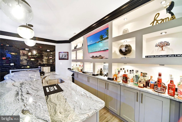 bar with light stone countertops, decorative light fixtures, gray cabinets, and sink