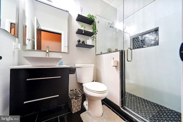 bathroom with vanity, toilet, and a shower with door