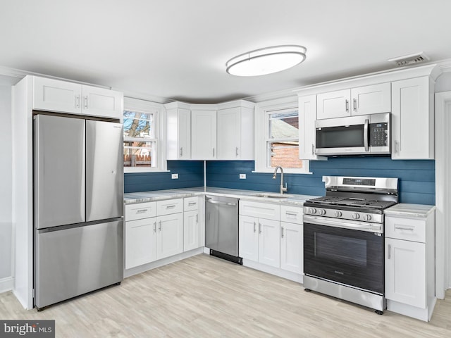 kitchen featuring white cabinets, stainless steel appliances, a healthy amount of sunlight, and sink