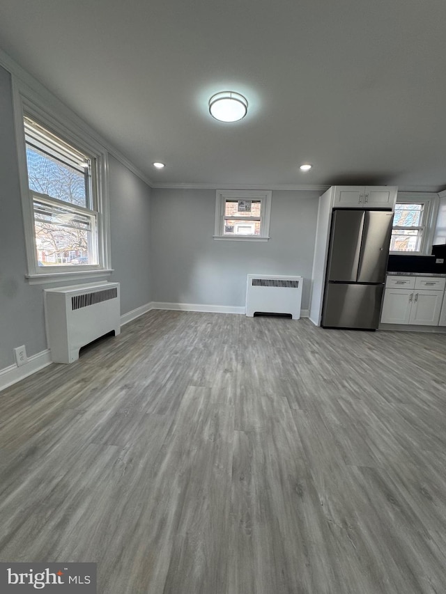 unfurnished living room with plenty of natural light, light wood-type flooring, and radiator heating unit