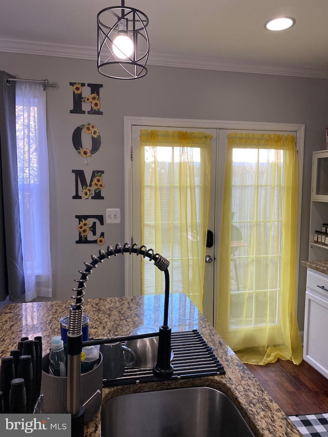 kitchen with stone counters, hanging light fixtures, and ornamental molding