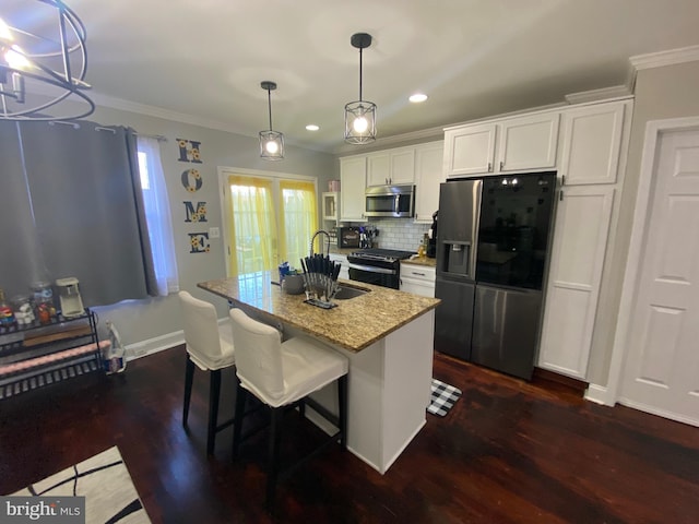 kitchen with pendant lighting, a center island with sink, white cabinets, crown molding, and appliances with stainless steel finishes