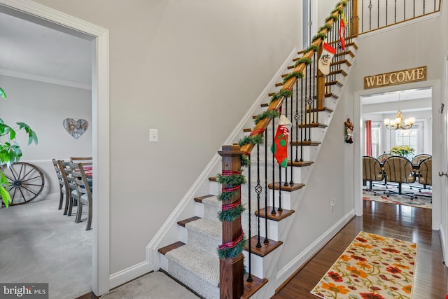 staircase featuring hardwood / wood-style floors, a notable chandelier, and ornamental molding