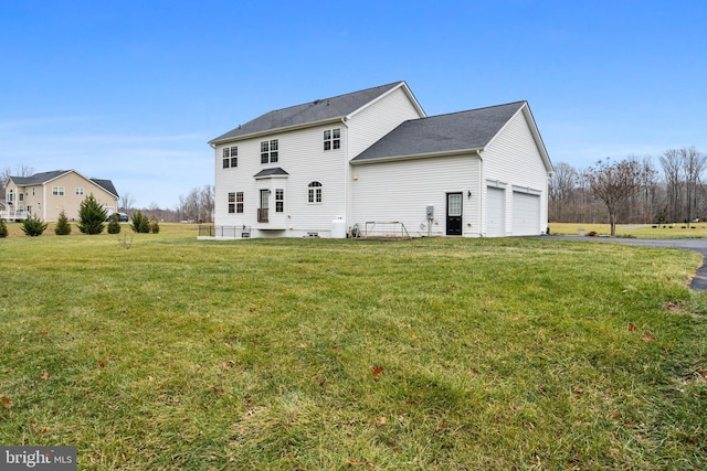 rear view of property with a garage and a yard