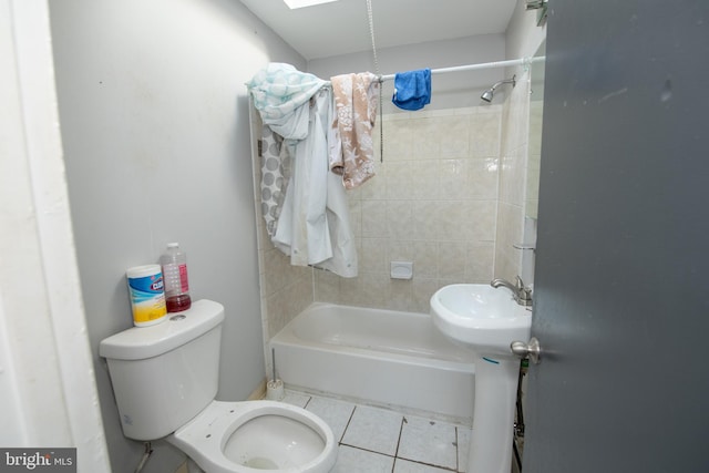 full bathroom with sink, tiled shower / bath, a skylight, tile patterned flooring, and toilet