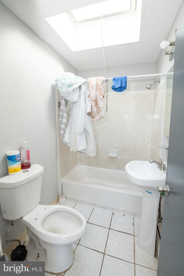 bathroom featuring a skylight, tile patterned flooring, tiled shower / bath combo, and toilet