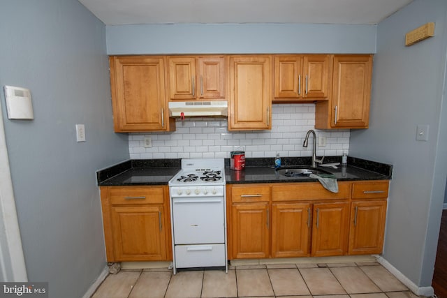 kitchen featuring dark stone counters, tasteful backsplash, gas range gas stove, and sink