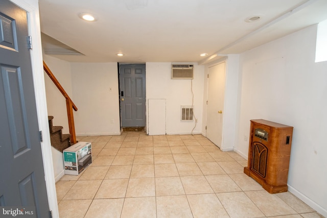 basement with a wall mounted air conditioner and light tile patterned floors