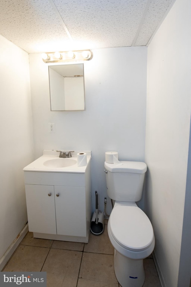 bathroom with tile patterned floors, a paneled ceiling, vanity, and toilet