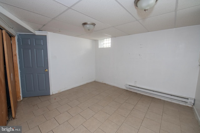 basement with a paneled ceiling and baseboard heating