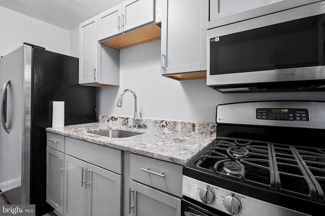 kitchen with white cabinets, light stone counters, sink, and stainless steel appliances