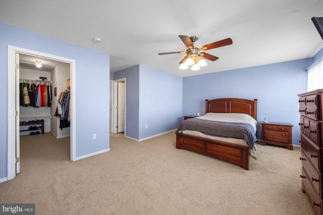 bedroom with a walk in closet, light colored carpet, a closet, and ceiling fan