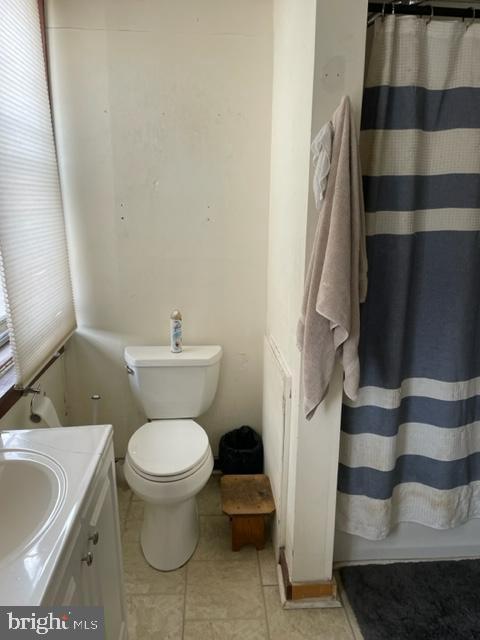 bathroom featuring tile patterned floors, toilet, vanity, and walk in shower