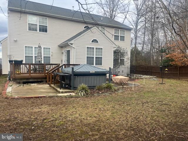 rear view of property with a lawn, a deck, and a hot tub