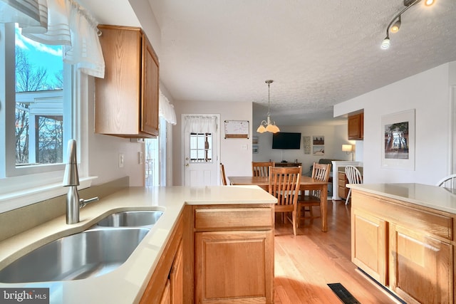 kitchen with kitchen peninsula, sink, pendant lighting, and plenty of natural light