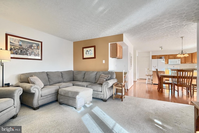 living room with light colored carpet, a textured ceiling, and an inviting chandelier