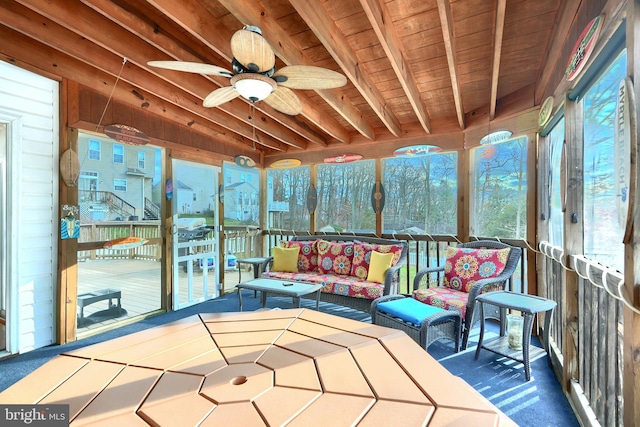 sunroom / solarium featuring beamed ceiling, ceiling fan, and wooden ceiling