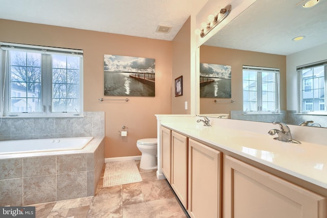 bathroom with tiled tub, vanity, and toilet