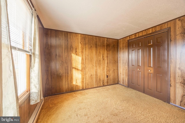 unfurnished bedroom with light carpet, wooden walls, and a closet