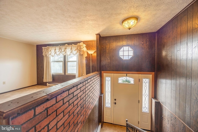 foyer entrance with a wealth of natural light, wood walls, and a baseboard radiator