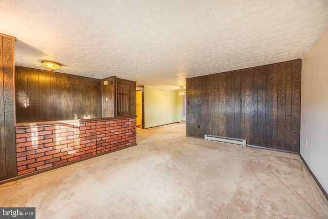 carpeted spare room featuring a textured ceiling, a baseboard radiator, and wooden walls