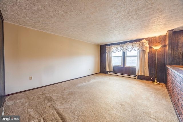 carpeted empty room featuring baseboard heating, wood walls, and a textured ceiling