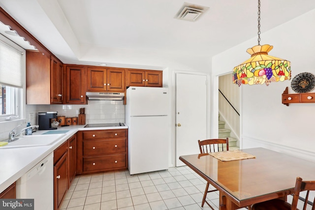 kitchen with decorative backsplash, white appliances, sink, light tile patterned floors, and hanging light fixtures