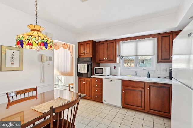 kitchen with white appliances, backsplash, sink, light tile patterned floors, and decorative light fixtures