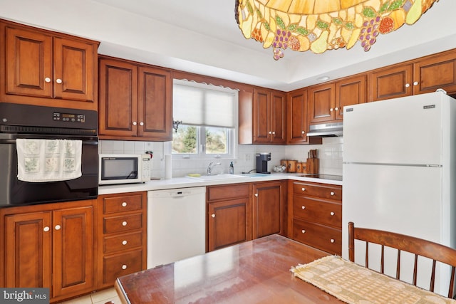 kitchen with sink, tasteful backsplash, a notable chandelier, and black appliances