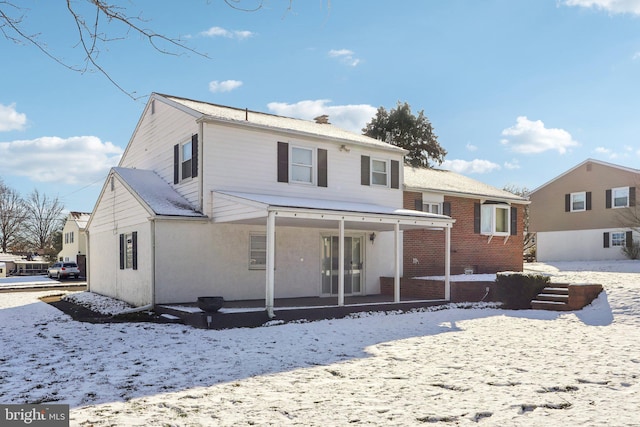 snow covered rear of property with a porch