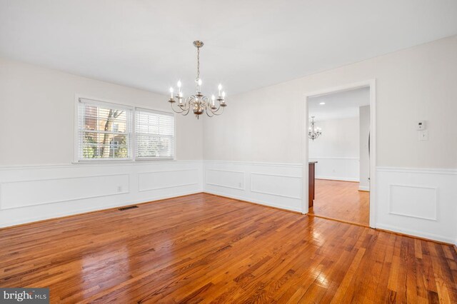 unfurnished room with hardwood / wood-style floors and an inviting chandelier