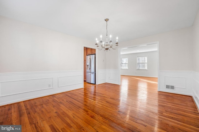 spare room featuring light wood-type flooring and a chandelier