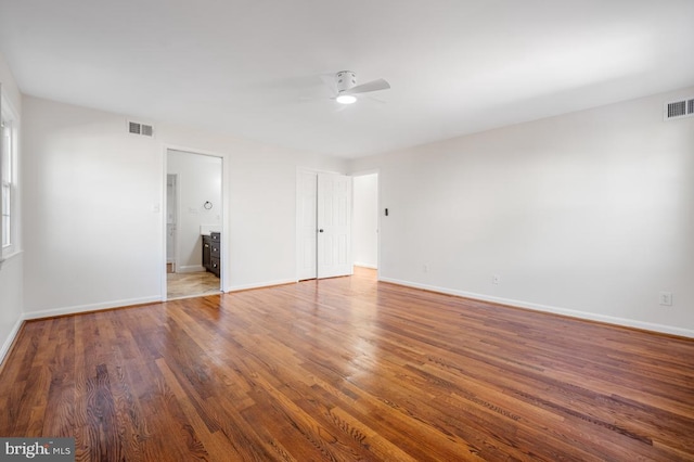 unfurnished bedroom with dark wood-type flooring, ensuite bath, and ceiling fan