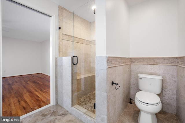 bathroom featuring toilet, an enclosed shower, tile patterned flooring, and tile walls