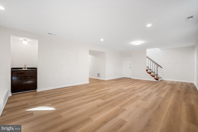 unfurnished living room featuring sink and light hardwood / wood-style floors