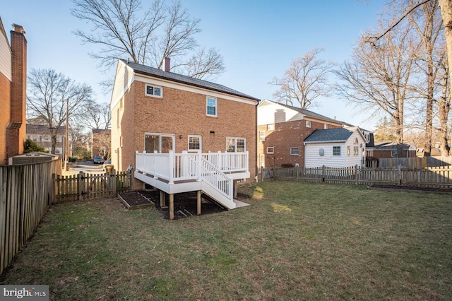 rear view of house featuring a wooden deck and a lawn