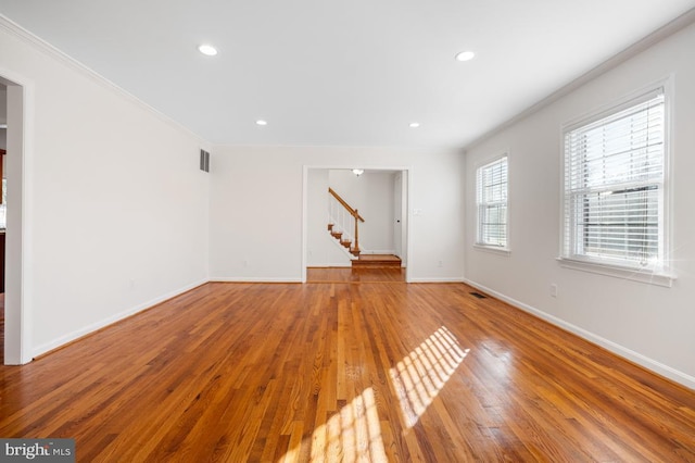 unfurnished living room featuring wood-type flooring and ornamental molding