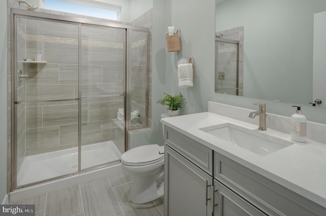 bathroom featuring tile patterned floors, vanity, toilet, and a shower with door