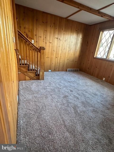 interior space with beamed ceiling and wood walls