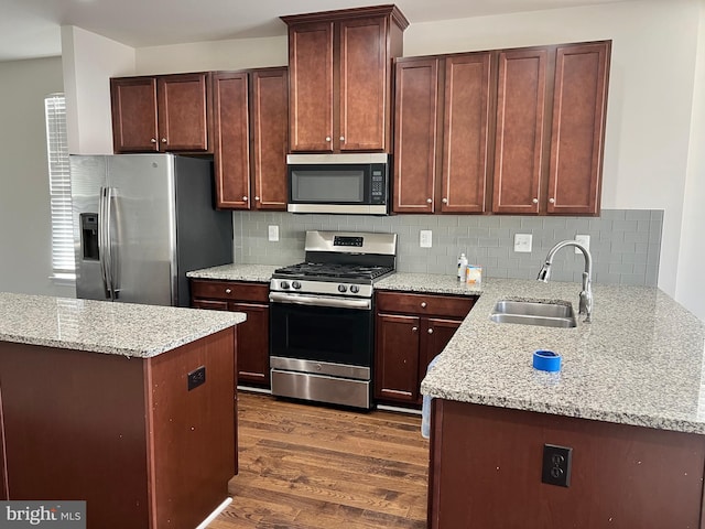 kitchen featuring light stone countertops, appliances with stainless steel finishes, decorative backsplash, dark wood-type flooring, and sink