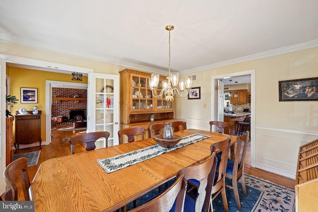 dining area featuring light hardwood / wood-style flooring, ornamental molding, and a notable chandelier