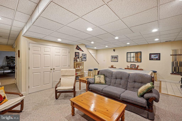 living room featuring a drop ceiling and light carpet