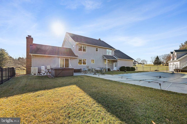 rear view of house with a swimming pool with hot tub, a yard, and a patio