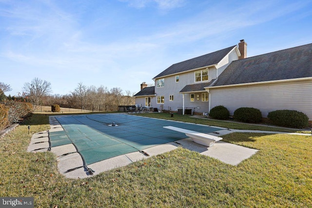 view of pool featuring central AC unit, a diving board, a patio area, and a yard