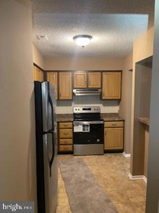 kitchen featuring stainless steel electric range oven, a textured ceiling, and fridge