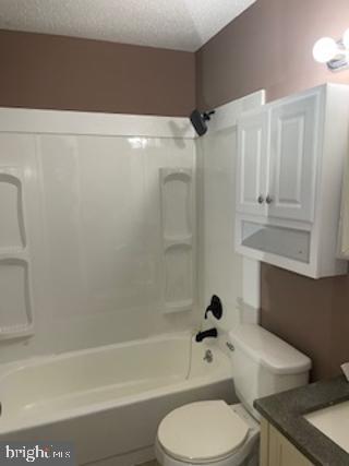 full bathroom with vanity, toilet, shower / bath combination, and a textured ceiling